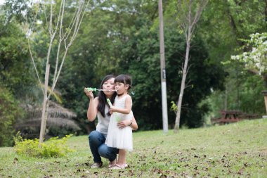 Asya aile açık havada etkinlik. Anne ve kızı Bahçe park adlı sabun köpüğü üfleme. 