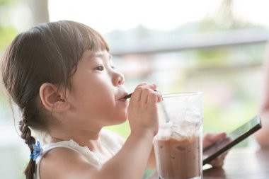 Küçük Asyalı kız café'de soğuk çikolata içme. Doğal ışık açık hava yaşam tarzı.