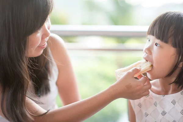 Mom パンをカフェで彼女の子供に供給 自然光でアジア家族アウトドア ライフ スタイル — ストック写真