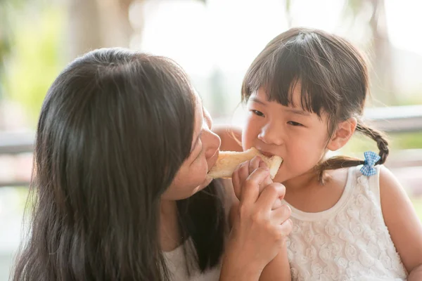 かわいいアジアの子の食事やカフェでママとバター トーストを共有します 自然光で家族アウトドア — ストック写真