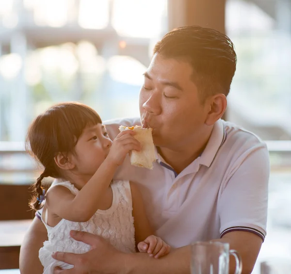 食堂でパパにパンを餌の娘 自然光でアジア家族アウトドア ライフ スタイル — ストック写真