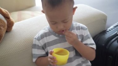 İki ya da üç yaşında Asyalı çocuk tahıl yemek, öz görüntüleri video besleme puffs.
