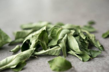 Kurutulmuş köri yapraklarını kapat, gri arka planda Hint baharatları. 