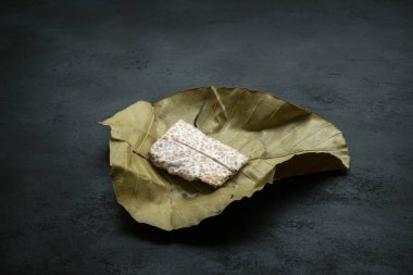 Taze çiğ bezelye Tempeh 'i Dilenia Suffruticosa yaprağına sarılmış, koyu arka plan.