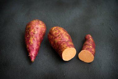 Koyu arkaplanda çiğ portakallı tatlı patatesler..