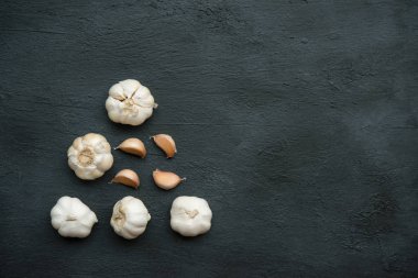 Üst görünüm sarımsak karanfilleri ve koyu arkaplanda kopyalama alanı olan ampul.