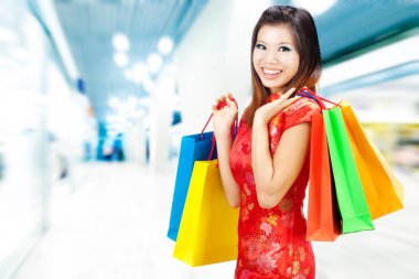 Geleneksel Çin Cheongsam marka kırmızı elbiseli bir kadın alışveriş merkezinde duruyor..