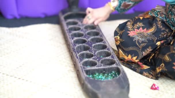 女子手玩康卡克 传统的马来两个玩家游戏 其中种子或大理石被扔进凹陷雕刻成船形的木板 — 图库视频影像