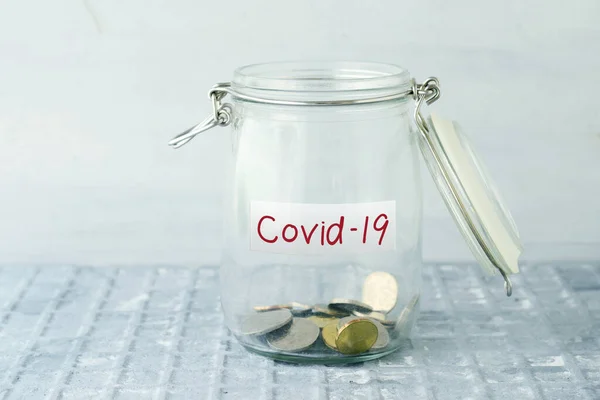 Covid19ラベル付きガラスマネージャーのコイン 金融コンセプト ストック画像