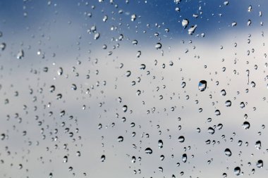 Mavi gökyüzüne karşı camına yağmur damlaları