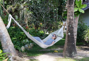 İki palmiye ağacı arasında bir hamakta kız