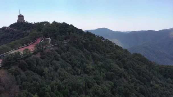 Cappella sulla cima di una montagna. Monastero in montagna. Foresta in cima alla montagna. Il drone vola sulle montagne. Turisti in cima alla montagna. Croce in cima alla montagna — Video Stock