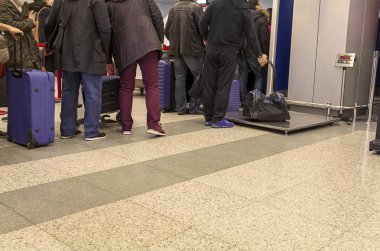 Sorgu odasındaki insanlar havaalanında bavullarını ve görüntülerini bekliyorlar. 