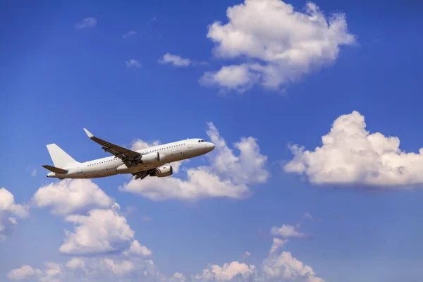 Белый пассажирский коммерческий самолет в полете. Самолет летит на фоне облаков. Вид сбоку самолета. - Образ — стоковое фото
