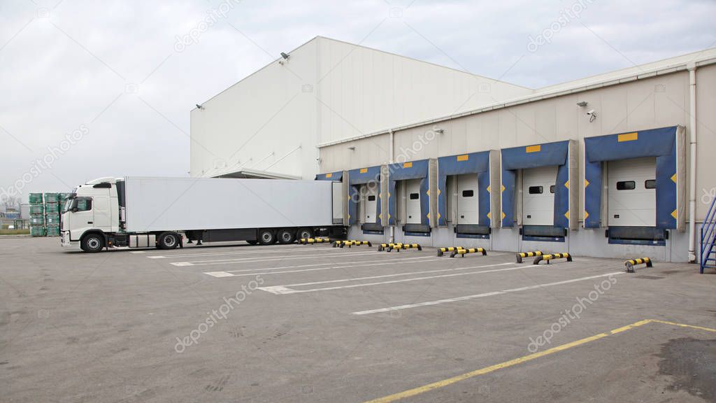 White Semi Truck Trailer at Warehouse Loading Ramp