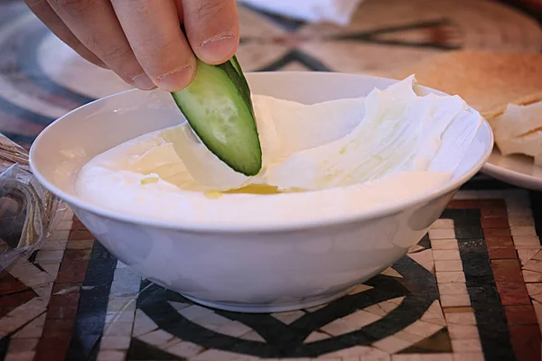 Ein Mann Taucht Eine Gurkenscheibe Einen Labneh Teller — Stockfoto