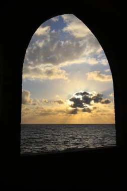 Batroun, Lübnan'daki bir kemer ile Akdeniz üzerinden günbatımı görünümünü.