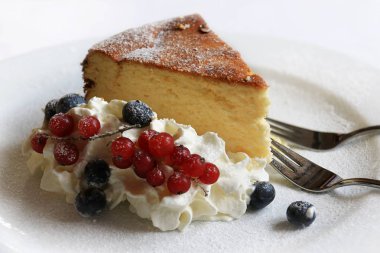 Bir dilim pasta krema üzerinde yan ve yaban mersini ve kırmızı kuş üzümü ile.