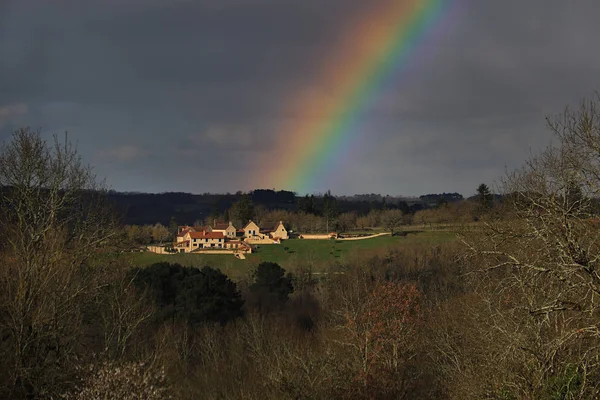 A rainbow after rain with a picturesque French village at its end.