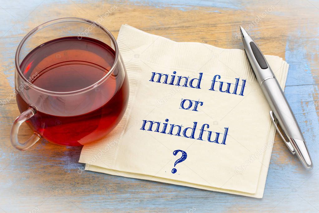 Mind full or mindful ? Inspiraitonal handwriting on a napkin with a cup of tea.