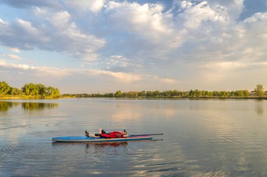 Erkek paddler Kuzey Colorado, yaz sahne sakin gölde bir paddleboard dinlenme