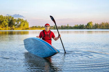 Çevre Kuzey Colorado, yaz sahne sakin gölde paddleboard kadar bir stand ile üst düzey bir erkek paddler portresi