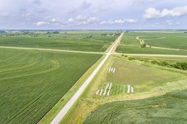 aerial view of rural Nebraska landscape with a farm road, soybean field and hay bales clipart