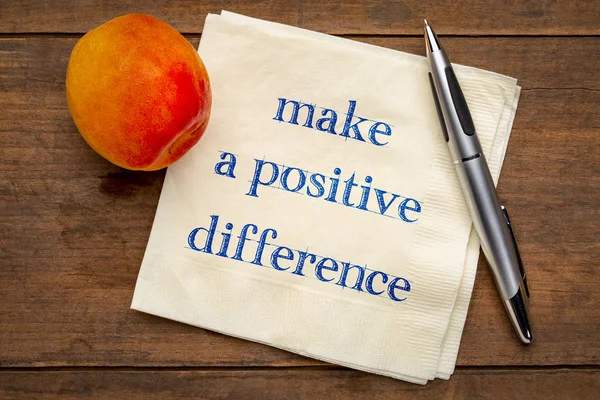 make a positive difference - inspiraitonal handwriting on a napkin with a fresh apricot fruit