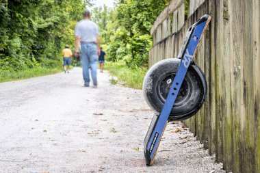 Rocheport, MO, USA - July 29, 2018: Oneweel electric skateboard on Katy Trail converted from abandoned railroad. clipart