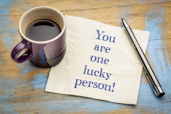 You are one lucky person! Positive affirnation concept -  handwriting on a napkin with a cup of espresso coffee