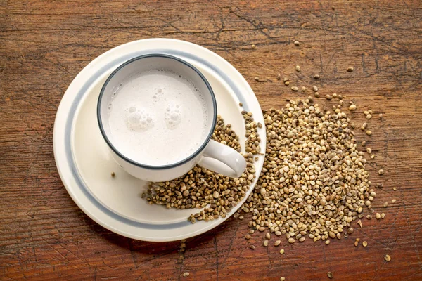 a cup of hemp milk and hemp seeds on a grunge wood