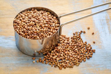 glutn ücretsiz buğday kaşa ahşap arka plan karşı ölçme Kepçe (1/4 su bardağı)