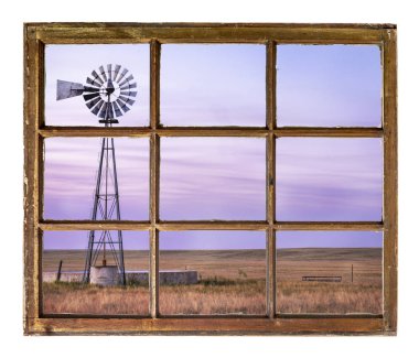 shortgrass Prairie pompa ve sığır su deposu ile gece karanlığında bir vintage kabin penceresinden görüldüğü gibi yel değirmeni
