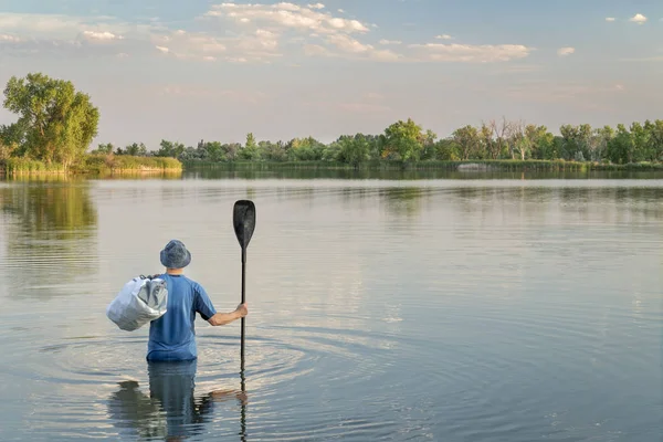 パドルと防水ダッフル立って腰の深い水 ボートや周り Paddleboard を持つ男 — ストック写真