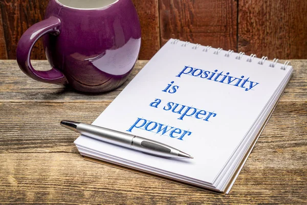 Positivity is a super power  - text in a sketchbook with a mug of hot tea or coffee