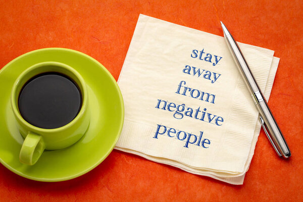 stay away from negative people - handwriting on a napkin with a cup of coffee