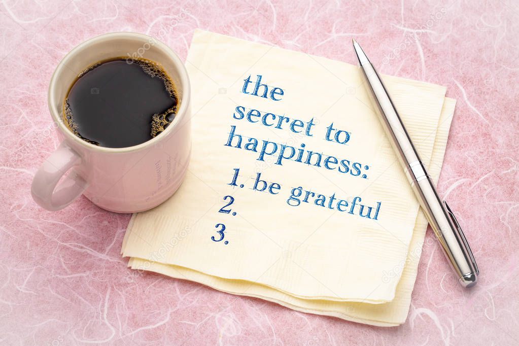 the secret to happiness concept - handwriting on a napkin with a cup of espresso coffee