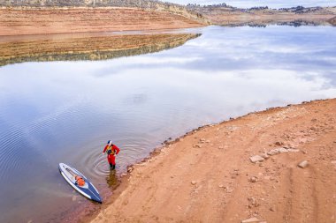 Bir stand paddler Gölü kıyısında bir drysuit içinde hiçbir kar ve düşük su seviyesi ile Kuzey Colorado eteklerinde tipik kış manzarası kadar havadan görünümü