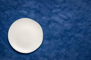 koyu mavi el yapımı Huun Maya Kağıt kopya alanı ile düzensiz bir kenar ile beyaz seramik tabak