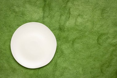 Beyaz seramik tabak yeşil yosun düzensiz bir kenar ile el yapımı Huun Maya Kağıt kopya alanı ile