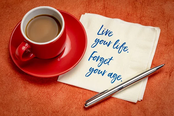 Live your life, forger your age - handwriting on a napkin with a cup of coffee