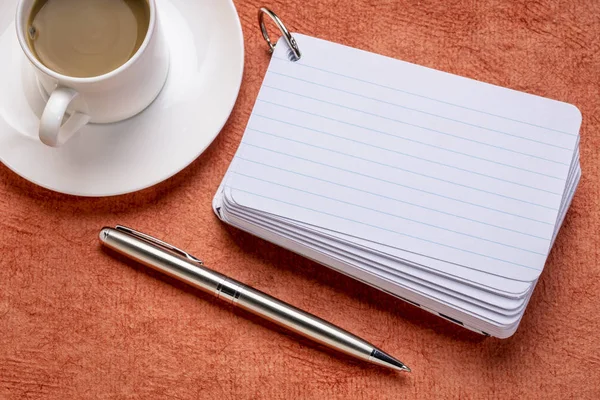 a stack of blank index cards with a cup of coffee and  a pen against textured bark paper