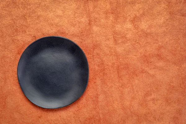 Zwarte Keramische Plaat Met Een Onregelmatige Rand Een Pompoen Oranje — Stockfoto