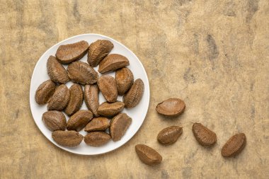 Bir kopya alanı ile güderi dokulu kağıt arka plan beyaz tabakta Brezilya fındık