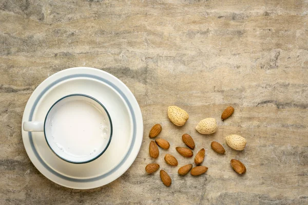 Tasse Mandelmilch Mit Nüssen Gegen Texturiertes Rindenpapier Mit Kopierraum — Stockfoto