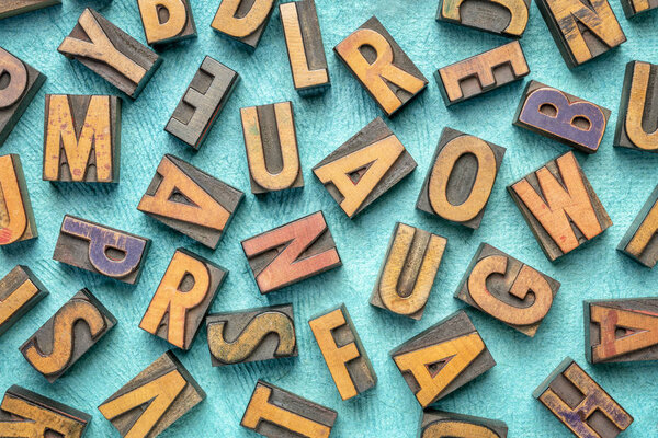 random letters overhead background - vintage letterpress wood type (inverted image)  against tuquoise bark paper