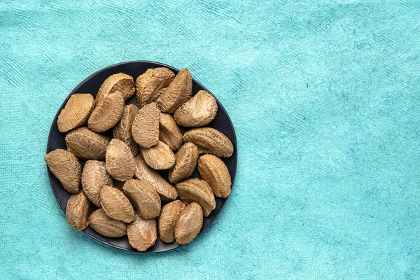 Brazilian nuts on a black plate — Stock Photo, Image