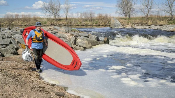 Paddler portage planche à pagaie sur la rivière rapide — Photo