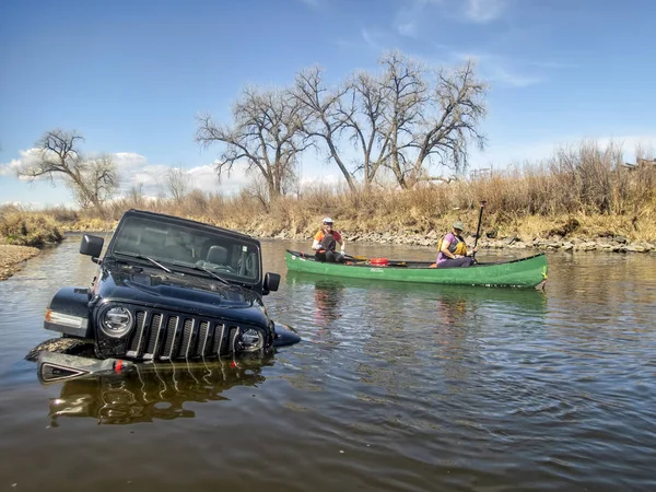 Paddlers in canoe passing stuck Jeep Wrngler — Stock Photo, Image