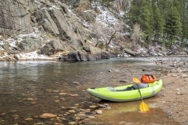bir dağ nehrinin kayalık kıyısında şişme Whitewater kayık